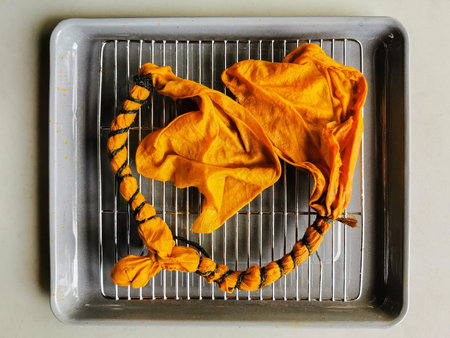Tie-dye cotton fabric after dyeing with Curcumin on stainless grille on the gray tray. Resulting in...
