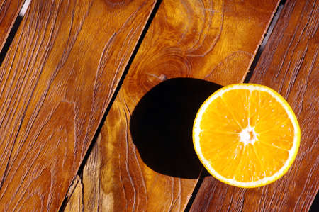 A sweet orange on the teak wood table. Macro photography.の写真素材