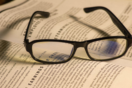 Yogyakarta, Indonesia - March 3, 2021: Black glasses on the old economic book on blurry backgroundのeditorial素材