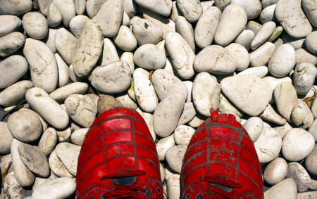 A pair of red broken shoes on white gravelの写真素材