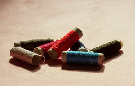 Multicolor sewing threads on pink background, backlight