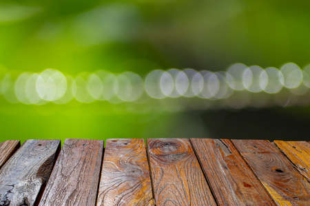 Old teak wood empty table in front of green bokeh background for display of productの写真素材