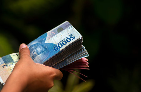 An Asian child holds Indonesian money, in shallow focus. Saving and giving concept