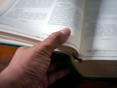 A thumb flipping pages of a book in shallow focus, educational backgroundの写真素材