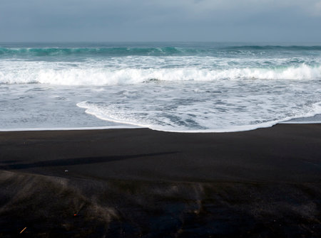 Dark sandy seashore on Parangtritis Beach, in Yogyakarta, Indonesiaの写真素材