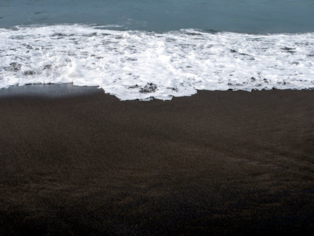 Dark sandy seashore on Parangtritis Beach, in Yogyakarta, Indonesiaの写真素材