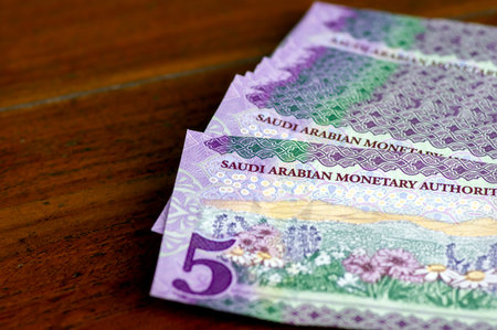 A pile of Saudi Arabia five riyals banknotes money on wooden table, selected focus