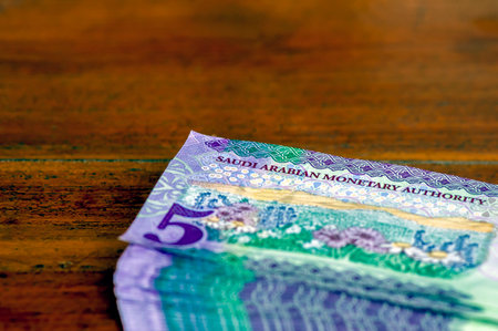 A pile of Saudi Arabia five riyals banknotes money on wooden table, selected focusの写真素材