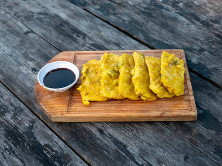 Tempe Goreng Tepung, Tempe Mendoan, flour fried tempeh, tradtional food from Indonesia, on wooden board and vintage table.の写真素材
