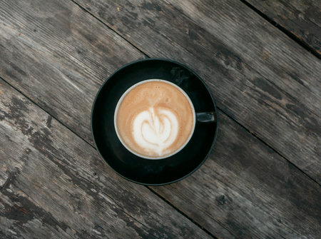 A coffee late art with vintage tone in a black mug on an old wooden tableの写真素材