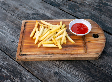 French fries with hot organic tomato and chilli sauce on an old vintage wooden tableの写真素材