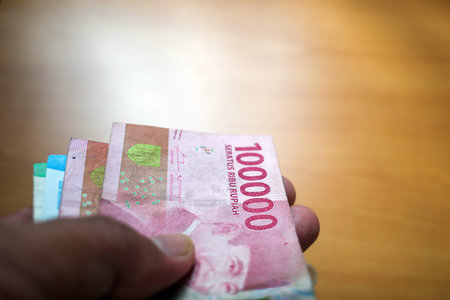 An Asian man holds Indonesian money, in shallow focus. Saving and giving concept.