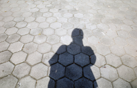 A shadow of person standing on the block floor, in the morning.