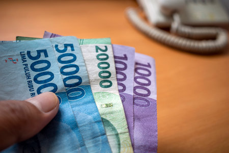 An Asian man holds Indonesian money, in shallow focus. Saving and giving concept.の写真素材