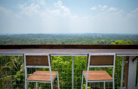 Two empty wooden chairs to sit and enjoy the view from the top of the hillの写真素材