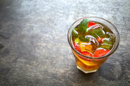A glass of strawberry smoothie ice garnished with fresh mint and sliced strawberries on an old wooden table.の写真素材
