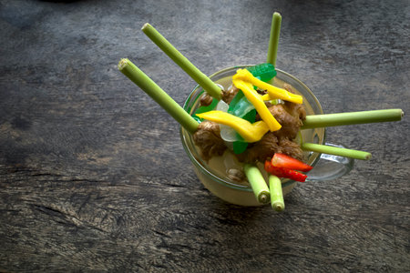 A glass of herbal drink with lemongrass, tea, ginger, honey and strawberry topping, on an old woden table.の写真素材