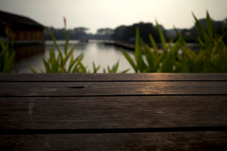 Wooden board empty table in front of a green park and an artificial lake for product display.の写真素材