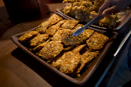 Close up of Tempe Garit Goreng (fried soybean cake) on a clay pan. Indonesian traditional food.の写真素材