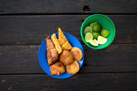 Various traditional fried food, Gorengan from Indonesia, on a blue plastic plate and sliced lemon.