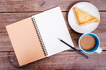 Cup of coffee, croissant and note on old wooden tableの写真素材