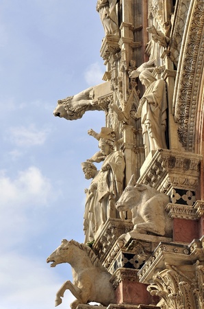The living facade of Siena Cathedral with monuments and reliefs of saints, animals, gargoyles and beautiful patterns. Siena, Tuscany, Italy.の写真素材