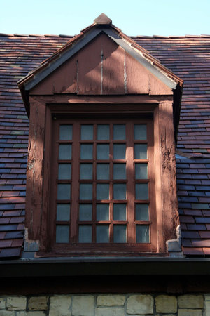 filtered light falls on this classic wood dormer on top of this stone building
