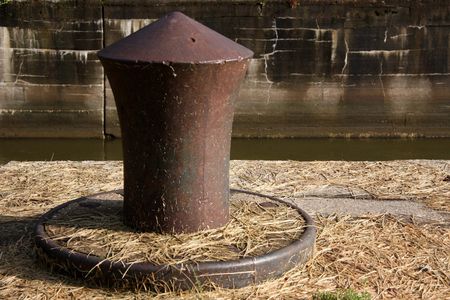 rusted aged boat tie down on the edge of an abandoned lock and dam.の写真素材