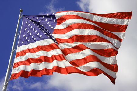 American Flag blows in the wind on the 4th of July with bright blue sky in the backgroundの写真素材