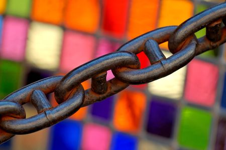 An old rusty chain in front of a coloured stained glassの写真素材