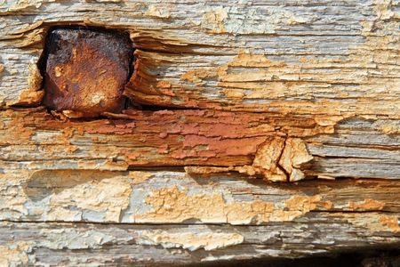 Some old painted and rusty boards in a boat cemetary with a large nailの写真素材