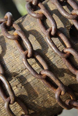 Rusty chain wrapped around a wooden hub in a windmillの写真素材