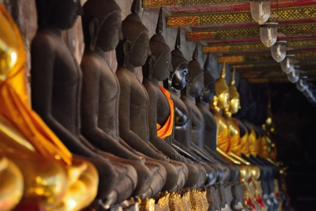 golden buddhas lined up along the wall of buddhist temple 
の写真素材