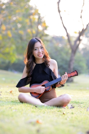 Asia women playing Ukulele in park outdoorの写真素材