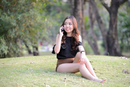 Asia women talking mobile phone in the parkの写真素材