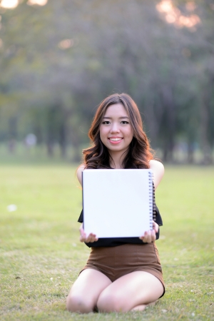 Asia woman show blank paper in the parkの写真素材
