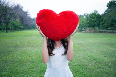 Women holding big love heart shape pillow in the parkの写真素材