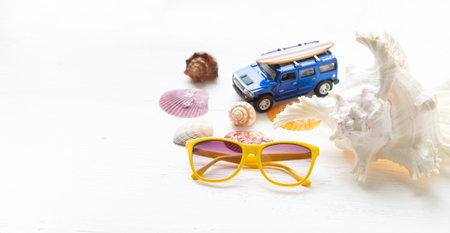 Yellow sunglasses and shells on a white wooden floor