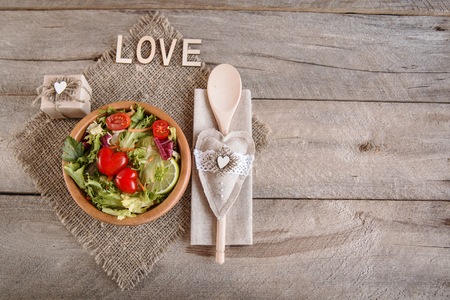 salad of organic vegetables for a loved one in a wooden dish on a wooden tableの写真素材