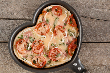 Pizza for Valentine's day with cheese, garlic parsley and pepper on old wooden backgroundの写真素材
