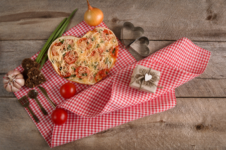 Pizza for Valentine's day with cheese, garlic parsley and pepper on old wooden backgroundの写真素材