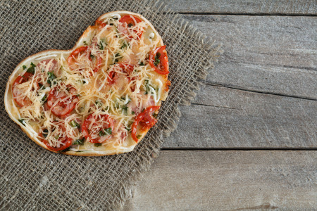 Pizza for Valentine's day with cheese, garlic parsley and pepper on old wooden backgroundの写真素材