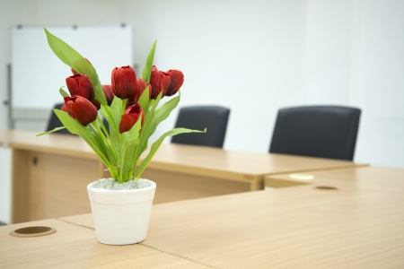 Two black chairs in a meeting room with Red flower on Meeting room tablet and white board in the backgroundの写真素材