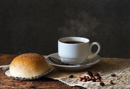 Still life with Hot Coffee in cup and coffee beans,bred on a wooden table.の写真素材