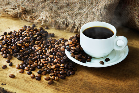 Hot Coffee cup and roast coffee beans on a wooden table and sack backgroundの写真素材