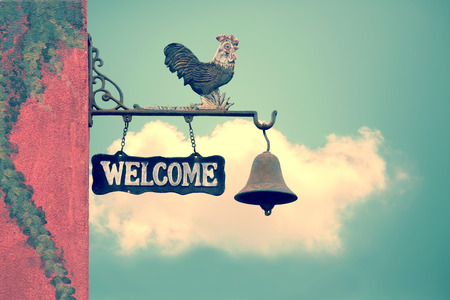 Classic Door Bell with silhouette  of  chicken, vintage welcome label  on blue sky with cloudの写真素材