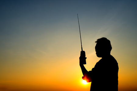 silhouette man with radio communication, sunset on blue sky backgroundの写真素材