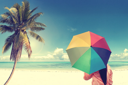 Girl on a sandy beach  with colorful rainbow umbrella, vintage effectの写真素材