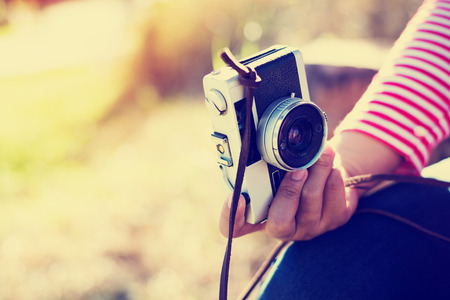 Vintage young hipster girl photographer hand holding retro camera