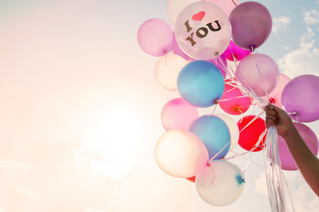 Woman hand holding balloon. I Love You symbol concept of love in valentine day - serenity and rose quartz color filter, vintage pastel effectの写真素材